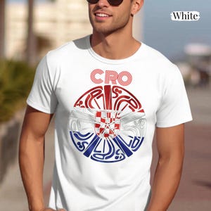 May include: A white short-sleeved t-shirt featuring a circular graphic on the chest. The design incorporates the red, white, and blue colors of the Croatian flag with a checkered pattern in the center and the text CRO in red above the circle.