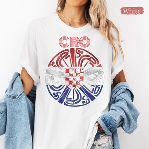 May include: A white short-sleeved t-shirt featuring a circular graphic design with the text CRO at the top. The graphic incorporates the red, white, and blue colors of the Croatian flag with a central red and white checkered shield emblem.