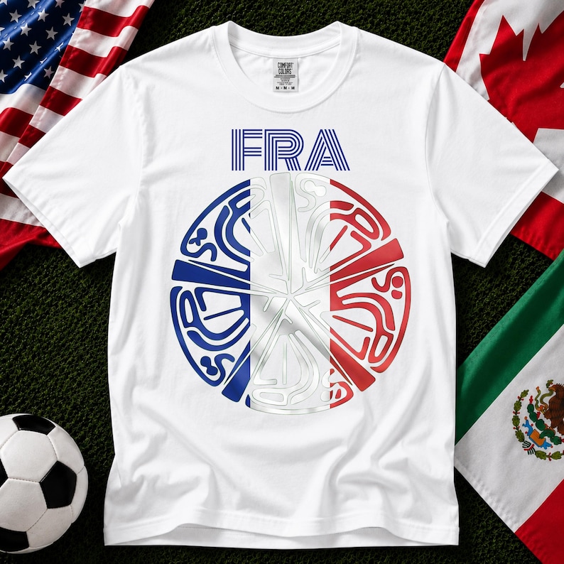 May include: A white short-sleeve t-shirt featuring the text FRA in blue stripes above a circular graphic. The circle is divided into vertical blue, white, and red sections with stylized, abstract line art patterns integrated throughout the design.