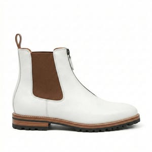 May include: White leather Chelsea boot with a zipper closure and brown elastic side panel. The boot has a brown sole and a pull tab at the back. The boot is approximately 6 inches tall.
