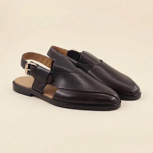 May include: A pair of black leather sandals with a closed-toe design and a slingback strap. The sandals feature a buckle closure and a tan insole. The shoes have a classic, elegant style.