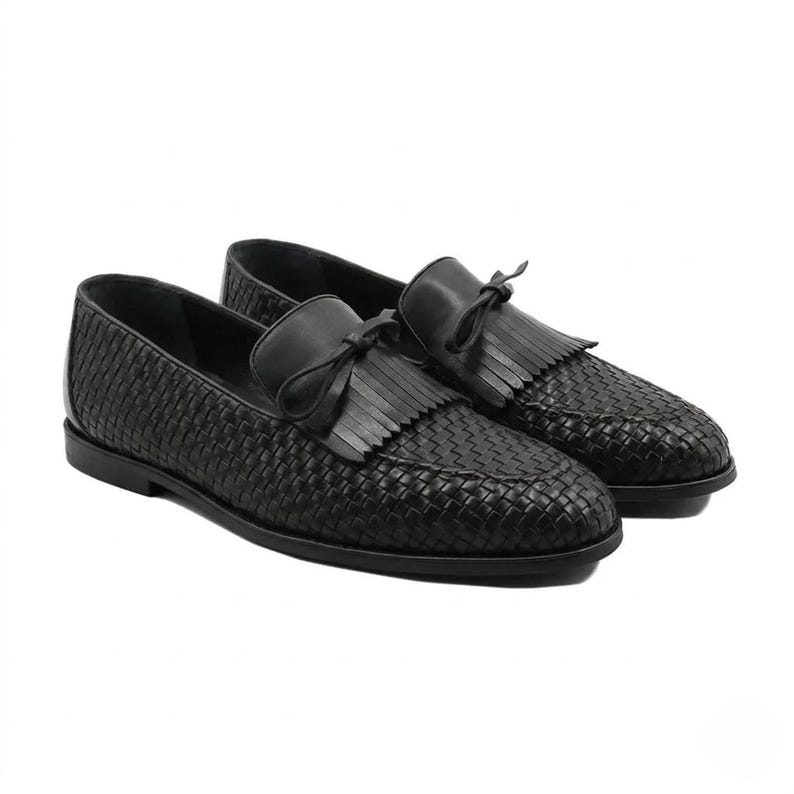 A pair of premium handmade black woven leather loafers for men featuring a traditional kiltie fringe and tassel tie. The shoes showcase a detailed hand-braided texture (intrecciato) on the body and a smooth leather tongue, set against a clean white background to emphasize the luxury craftsmanship.