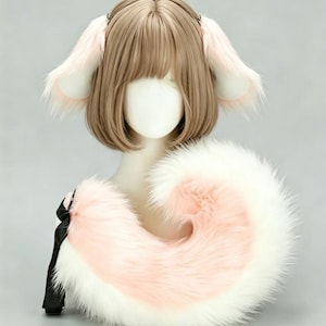 Könnte beinhalten: Ein Cosplay-Set mit einer Perücke mit hellbraunem Haar und befestigten flauschigen Ohren in Rosa und Weiß. Ein passender flauschiger Schwanz in Rosa und Weiß ist ebenfalls enthalten, befestigt mit einem schwarzen Band. Das Set wird auf einem Schaufensterkopf präsentiert.