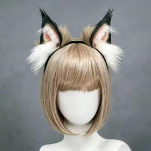 Puede incluir: Una diadema negra con orejas de lobo de piel sintética. Las orejas son una mezcla de marrón, negro y blanco, con detalles rosas en el interior. Las orejas son erguidas y esponjosas.