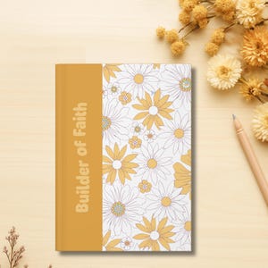 May include: A journal with a mustard yellow spine and the text "Builder of Faith" in a vertical orientation. The cover features a white background with a pattern of yellow and white daisies. A pencil and dried flowers are in the background.