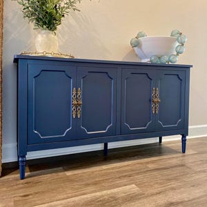 Könnte beinhalten: Ein Set aus drei Keramikbechern mit gesprenkelter, matter Oberfläche. Die Becher sind in Creme-, Hellgrau- und Dunkelgrautönen gehalten. Jeder Becher hat ein schlichtes, minimalistisches Design und einen abgerundeten Henkel.