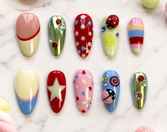 Speelse roze druk op de nagels met lieveheersbeestje, stippen en pastelkleurige strepen