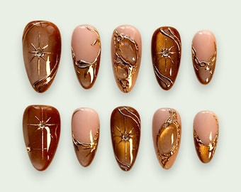 Plaknagels met metallic krullen in vintage barokstijl en kleine glinsterende strass-steentjes.