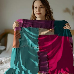 May include: A vibrant patchwork quilt with squares of teal, magenta, purple, and beige fabrics. The quilt has a wavy, irregular edge and is held up in front of a person. The quilt is made of various fabrics and stitched together with visible seams.