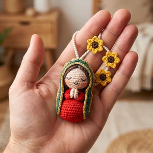 May include: A handcrafted crochet doll depicting the Virgin Mary, dressed in a red gown and a green and gold shawl. The doll is held in a hand and is attached to a string of white beads and yellow sunflower accents.