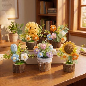 以下が含まれることがあります： 黄色、オレンジ、青、ピンク、白のクロッシェ編みの花を使った5つの小さな装飾用アレンジメント。木製の丸太の台座や、麻紐で飾られた白い質感のあるポットに植えられており、緑の布製の葉と茎が添えられています。