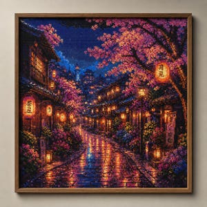 Op de afbeelding: Een ingelijste diamond painting van een Japanse straatscène 's nachts. Roze kersenbloesem bomen en gloeiende lantaarns verlichten de straat. Het kunstwerk is gevat in een houten lijst.