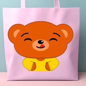 May include: A light pink tote bag featuring a cartoon bear face. The bear has orange fur, a yellow shirt, and a black nose and eyes. The bear's tongue is sticking out. The tote bag has pink handles.