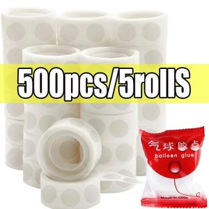 Puede incluir: Apilados de rollos de puntos adhesivos blancos con c&iacute;rculos grises, y un peque&ntilde;o paquete rojo y blanco de pegamento para globos. El texto "500pcs/5rolls" se muestra sobre un fondo amarillo.