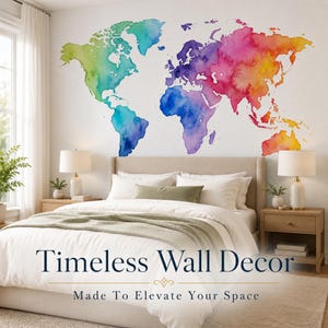Peut inclure: Un grand autocollant mural représentant une carte du monde dans un style aquarelle vibrant avec des dégradés de vert, bleu, violet, rose, orange et jaune. La carte est affichée sur un mur blanc au-dessus d'un lit avec une literie blanche.