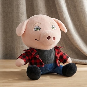Op de afbeelding: Een pluche varken met een lichtroze huid, groene ogen en een kleine glimlach. Het varken draagt een rood-zwart geruit overhemd over een donkergrijs t-shirt, gecombineerd met een blauwe broek in spijkerstof-stijl en zwarte pluche voeten.