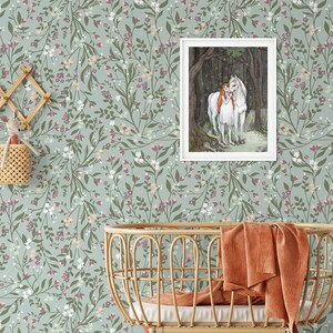 May include: A nursery room with a green floral wallpaper featuring a framed illustration of a girl and a white horse in a forest. The room also features a wicker crib with a burnt orange blanket, a white shelf with wicker baskets and a white panda-shaped storage box, and a white shelf with a white pitcher and a wicker basket.