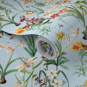 May include: A roll of wallpaper with a light blue background and a botanical design. The pattern features colorful flowers, dragonflies, and butterflies in shades of red, yellow, white, and green. The wallpaper is unrolled to reveal the pattern.