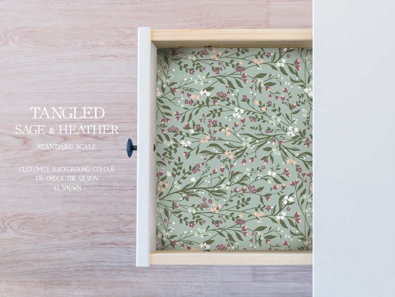 May include: A drawer liner with a sage green background and a floral pattern featuring white, pink, and burgundy flowers. The text "TANGLED SAGE & HEATHER STANDARD SCALE CUSTOMIZE BACKGROUND COLOUR OR ORDER THE DESIGN AS SHOWN" is printed on the drawer liner.