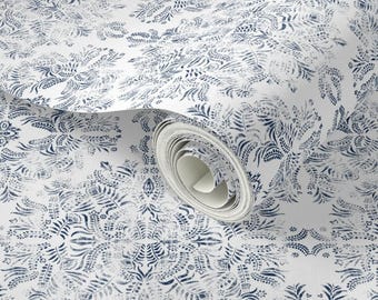 May include: White wallpaper roll with a repeating navy blue floral pattern. The design features stylized botanical elements arranged in a symmetrical layout. The roll is partially unrolled, revealing the pattern's continuity.