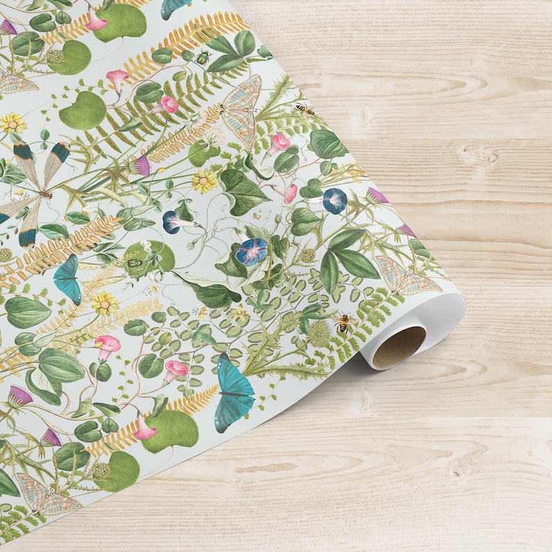 May include: A white wrapping paper with a repeating pattern of green leaves, yellow flowers, blue butterflies, and small insects. The paper is rolled up and the end is visible.