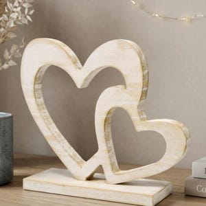 May include: A white ceramic mug with a black handle and the text "But First, Coffee" in a black, bold font. The mug is sitting on a wooden surface.