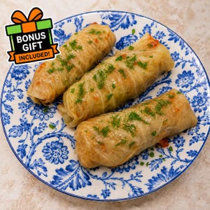 Puede incluir: Tres rollos de col cubiertos con hierbas verdes frescas en un plato blanco con un patrón floral azul. Un gráfico en la esquina superior izquierda presenta un lazo naranja y el texto BONUS GIFT INCLUDED! en letras blancas y negras.