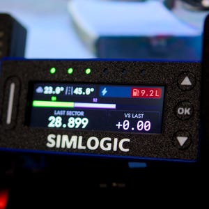 May include: A black rectangular Simlogic digital telemetry display unit with a textured finish. The screen shows data including 23.0 degrees, 45.0 degrees, 9.2L fuel, a last sector time of 28.899, and a vs last value of +0.00 with navigation buttons.