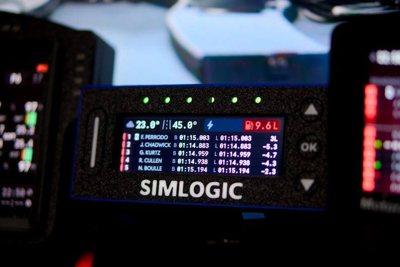 May include: A black Simlogic digital racing dashboard display featuring a rectangular screen with white text showing race standings, lap times, and fuel levels. The device has five green LED indicator lights along the top edge and navigation buttons.