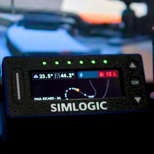 May include: A black rectangular Simlogic digital dashboard display with a textured finish. The screen shows a track map, fuel level of 12 L, and temperature readings of 23.5 and 44.2. Five green LED lights are positioned along the top edge of the device.