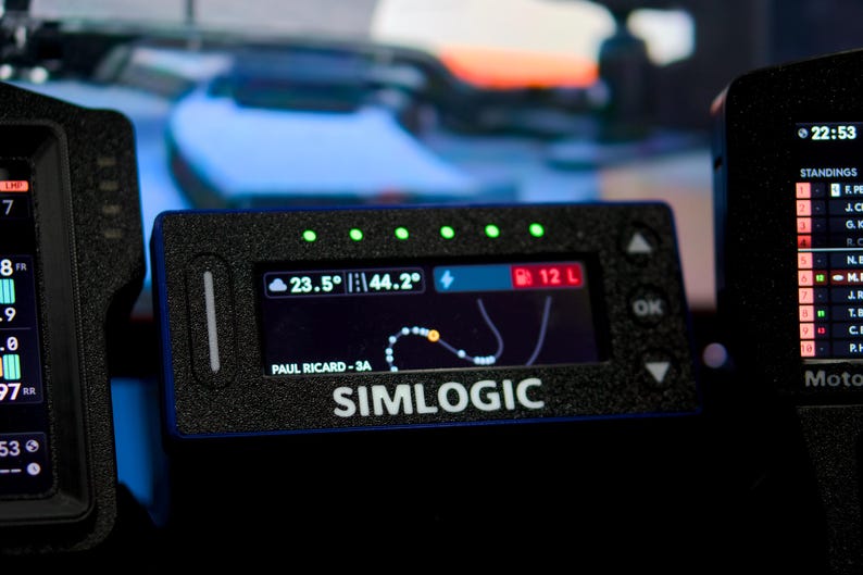 May include: A black rectangular Simlogic digital dashboard display with a textured finish. The screen shows a track map, fuel level of 12 L, and temperature readings of 23.5 and 44.2. Five green LED lights are positioned along the top edge of the device.