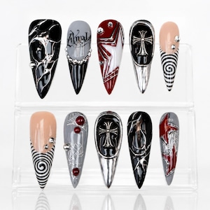 Unhas postiças ousadas em estilo gótico com padrões abstratos e detalhes em strass.