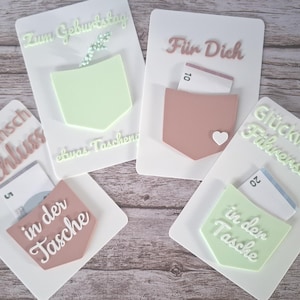 Peut inclure: Quatre cartes rectangulaires blanches avec des poches en relief vert pastel et vieux rose. Les cartes portent des textes en allemand tels que Zum Geburtstag, Für Dich, Glückwunsch Abschluss et Glückwunsch Führerschein, avec des billets insérés.