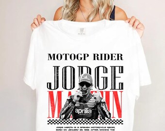 May include: A white t-shirt featuring a graphic of MotoGP rider Jorge Martin. The design includes the text MOTOGP RIDER JORGE MARTIN, a photo of the rider in racing gear, a checkered pattern, and a paragraph detailing his career history.