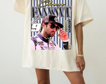 May include: An off-white short-sleeve t-shirt featuring a graphic print of race car driver Chase Elliott. The design includes the text Chase Elliott, the number 9, and Hendrick Motorsports branding over a blue and white vertical striped background.