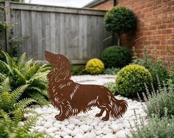 May include: A rust-colored metal silhouette of a long-haired dachshund dog standing in profile. The cutout design features detailed lines representing the fur texture, ears, and tail of the dog, creating a decorative garden ornament.