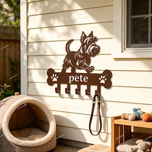 May include: A brown metal wall-mounted hook rack featuring a silhouette of a terrier dog standing above a bone-shaped bar. The bar displays the name pete in white lowercase letters, flanked by two white paw prints, with five hooks below.