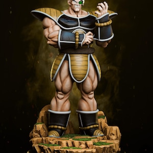 May include: A detailed figurine of a bald, muscular character with a green visor, wearing black and gold armour. The figure stands on a rocky base with patches of green, with the Tanuki Figures logo in the top left corner.