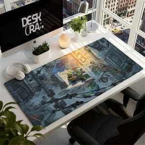 May include: A rectangular desk mat featuring a detailed cartoon illustration of the Teenage Mutant Ninja Turtles in a city setting. The mat has a blue and gray color scheme with the text "DESK ORA:" on the computer screen.