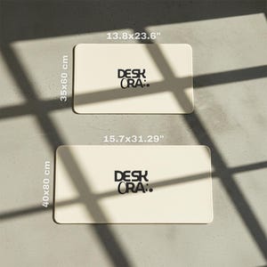 May include: Two rectangular cream-colored desk mats with rounded corners. The top mat measures 13.8 x 23.6 inches (35 x 60 cm), and the bottom mat is 15.7 x 31.29 inches (40 x 80 cm). Each mat has the text "DESK ORA:" in black.