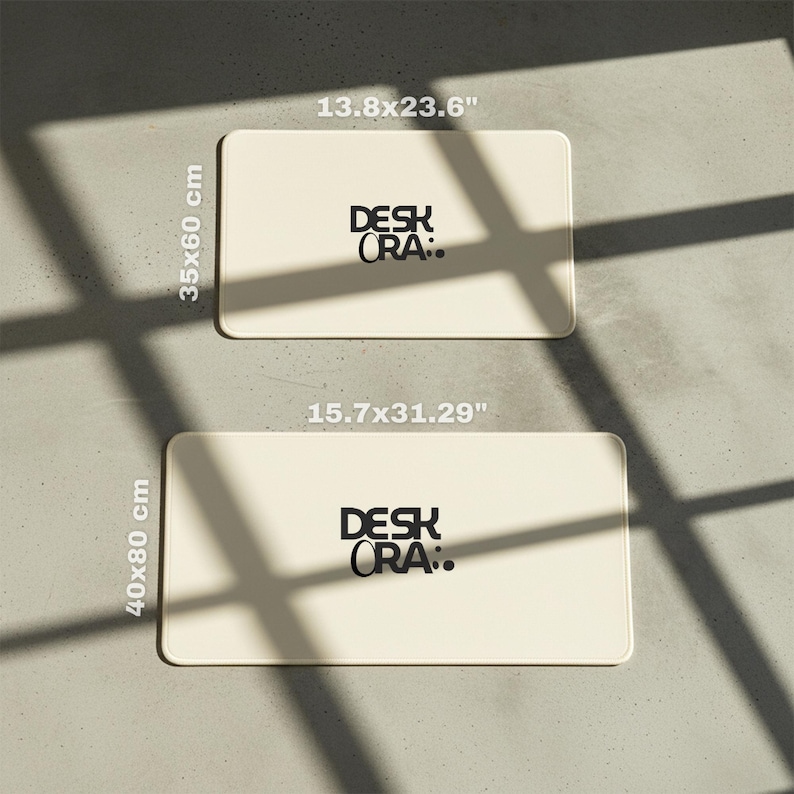 May include: Two rectangular cream-colored desk mats with rounded corners. The top mat measures 13.8 x 23.6 inches (35 x 60 cm), and the bottom mat is 15.7 x 31.29 inches (40 x 80 cm). Each mat has the text "DESK ORA:" in black.