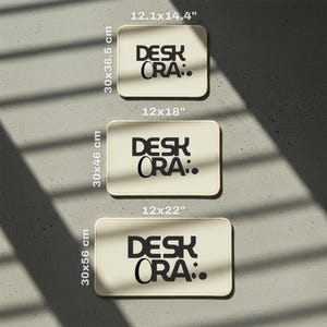 May include: Three rectangular desk mats in varying sizes are displayed. The mats are cream-colored with rounded corners and feature the text "DESK ORA." in black. The mats measure 12.1x14.4 inches, 12x18 inches, and 12x22 inches, with corresponding heights of 14.4, 18, and 22 inches.
