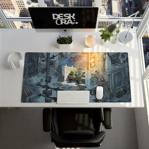 May include: A computer desk setup featuring a large mousepad with a detailed illustration of a street scene with cartoon characters. The desk also includes a computer monitor with the text "DESK ORA:.", a keyboard, mouse, and headphones.