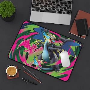 May include: A rectangular mousepad featuring a vibrant design with a dragon illustration in shades of blue, black, pink, and green. The mousepad has a black border and a white mouse is on top of it. A laptop, notebook, and coffee cup are also visible.