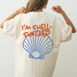 Camiseta "Estoy en shock por las conchas", camiseta divertida para la playa, camiseta con estampado de conchas marinas, camiseta veraniega costera, camiseta unisex para vacaciones en la playa, regalo para amantes del océano.