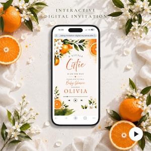 Peut inclure: Un smartphone affichant une invitation numérique interactive pour une fête prénatale avec des graphismes d'oranges et de fleurs blanches. Le texte indique A LITTLE CUTIE IS ON THE WAY, PLEASE JOIN US FOR A BABY SHOWER, HONORING OLIVIA.
