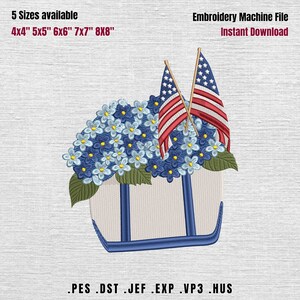 May include: An embroidery machine file featuring a floral design with blue flowers, green leaves, and two American flags. The design is in a white tote bag shape with blue accents. Text includes "5 Sizes available" and "Embroidery Machine File Instant Download."