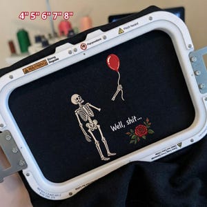 May include: An embroidery hoop holding black fabric with a white skeleton design, a red balloon, a red rose, and the text Well, shit... The hoop frame displays the text 4" 5" 6" 7" 8" at the top, along with various warning labels and parameters.