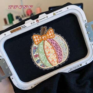 May include: An embroidery hoop holding black fabric with a stitched pumpkin design. The pumpkin features vertical panels of floral and patterned fabrics in orange, green, pink, and blue, topped with an orange plaid bow and a white lace border. Text reads 2" 3" 4" 5" 6".