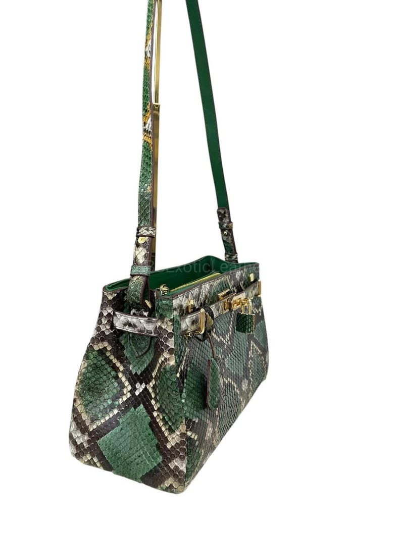 May include: A green and black snakeskin handbag with gold-tone clasps and handle hardware. The bag features a top handle and a long, adjustable shoulder strap. The bag is made of genuine snakeskin and has a structured shape.